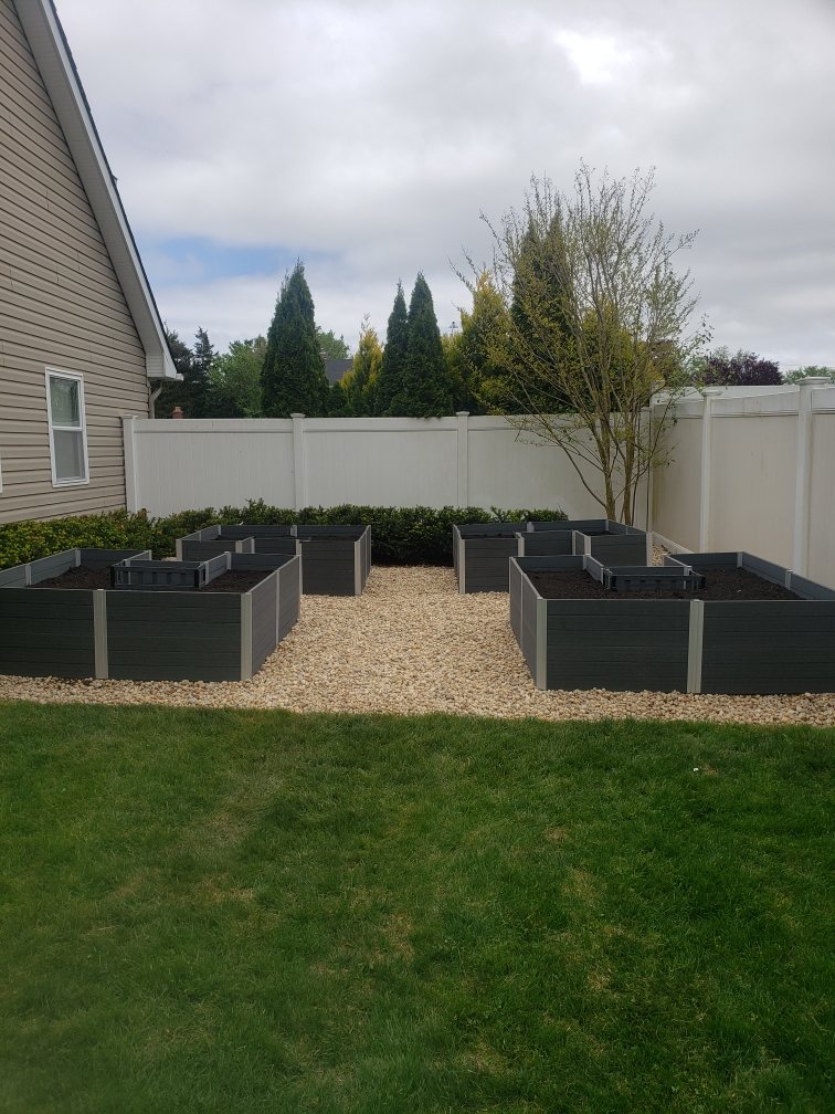 Raised garden beds surrounded by light stone and fresh soil