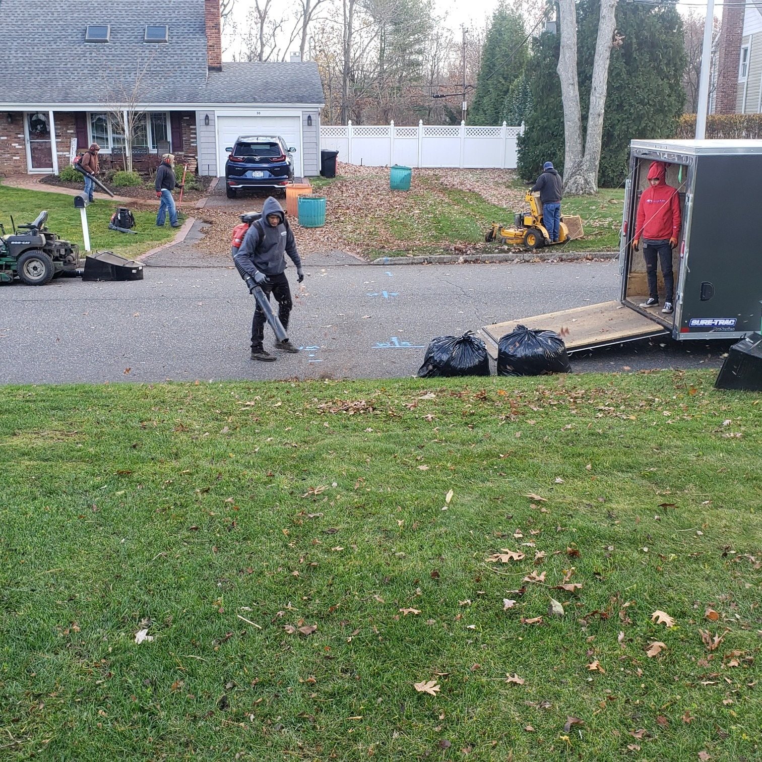 Crew handling a fall yard cleanup with leaf bags and equipment