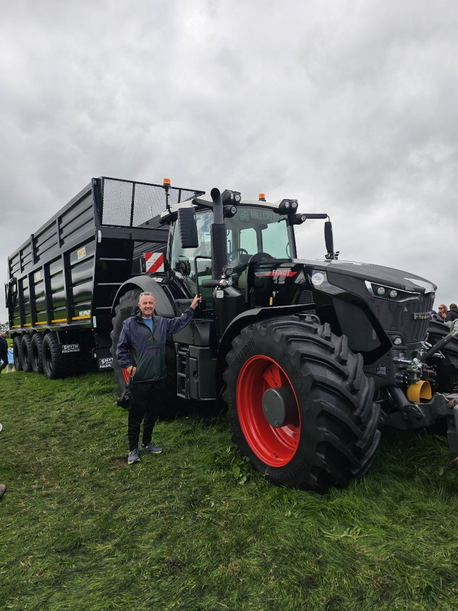 Thomas Burns standing beside a large landscaping tractor and trailer